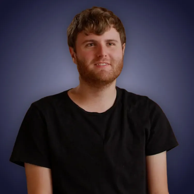Man with crossed arms wearing a black Tether shirt standing confidently in front of a wall with Tether logos.