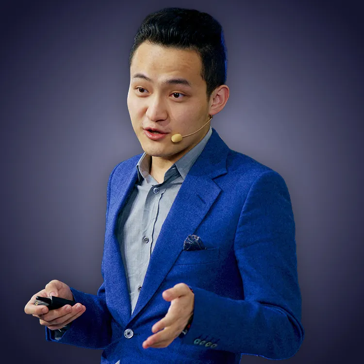 Man with crossed arms wearing a black Tether shirt standing confidently in front of a wall with Tether logos.