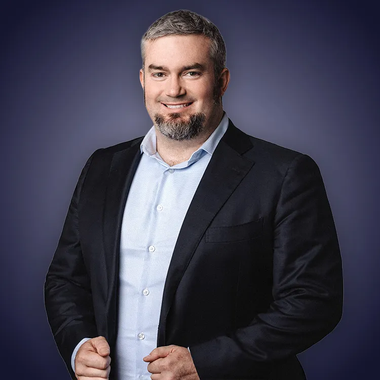 Man with crossed arms wearing a black Tether shirt standing confidently in front of a wall with Tether logos.