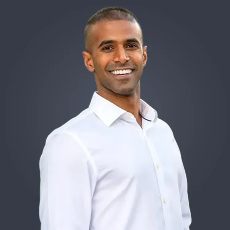 Man with crossed arms wearing a black Tether shirt standing confidently in front of a wall with Tether logos.