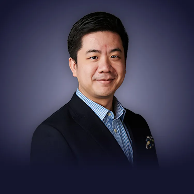 Man with crossed arms wearing a black Tether shirt standing confidently in front of a wall with Tether logos.